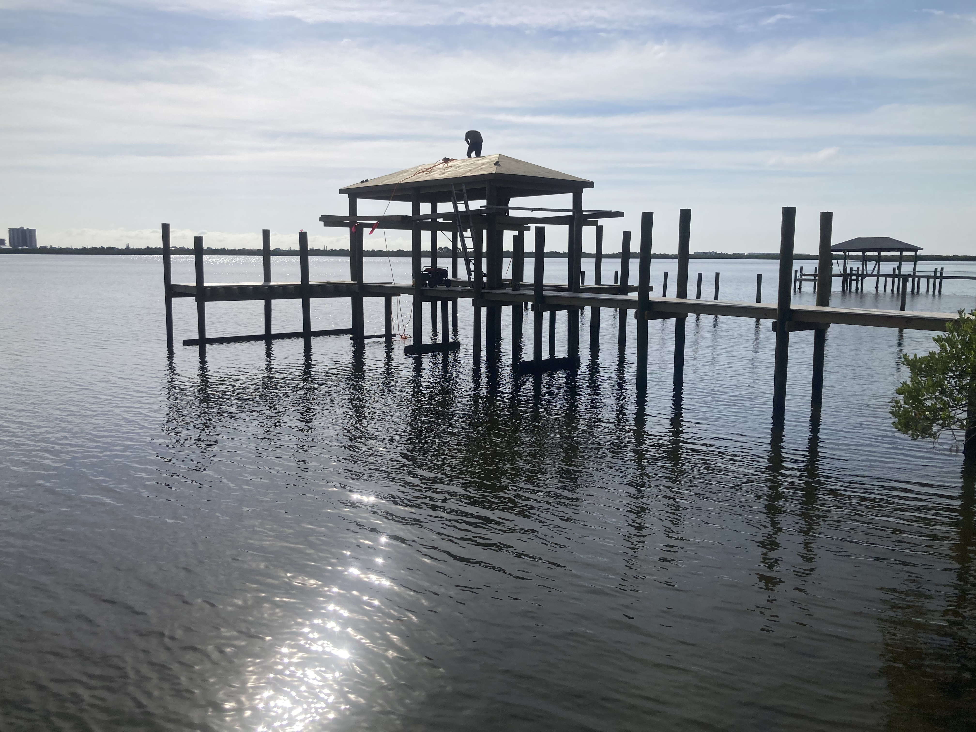Crew installing covered boathouse roof over open water dock, Florida