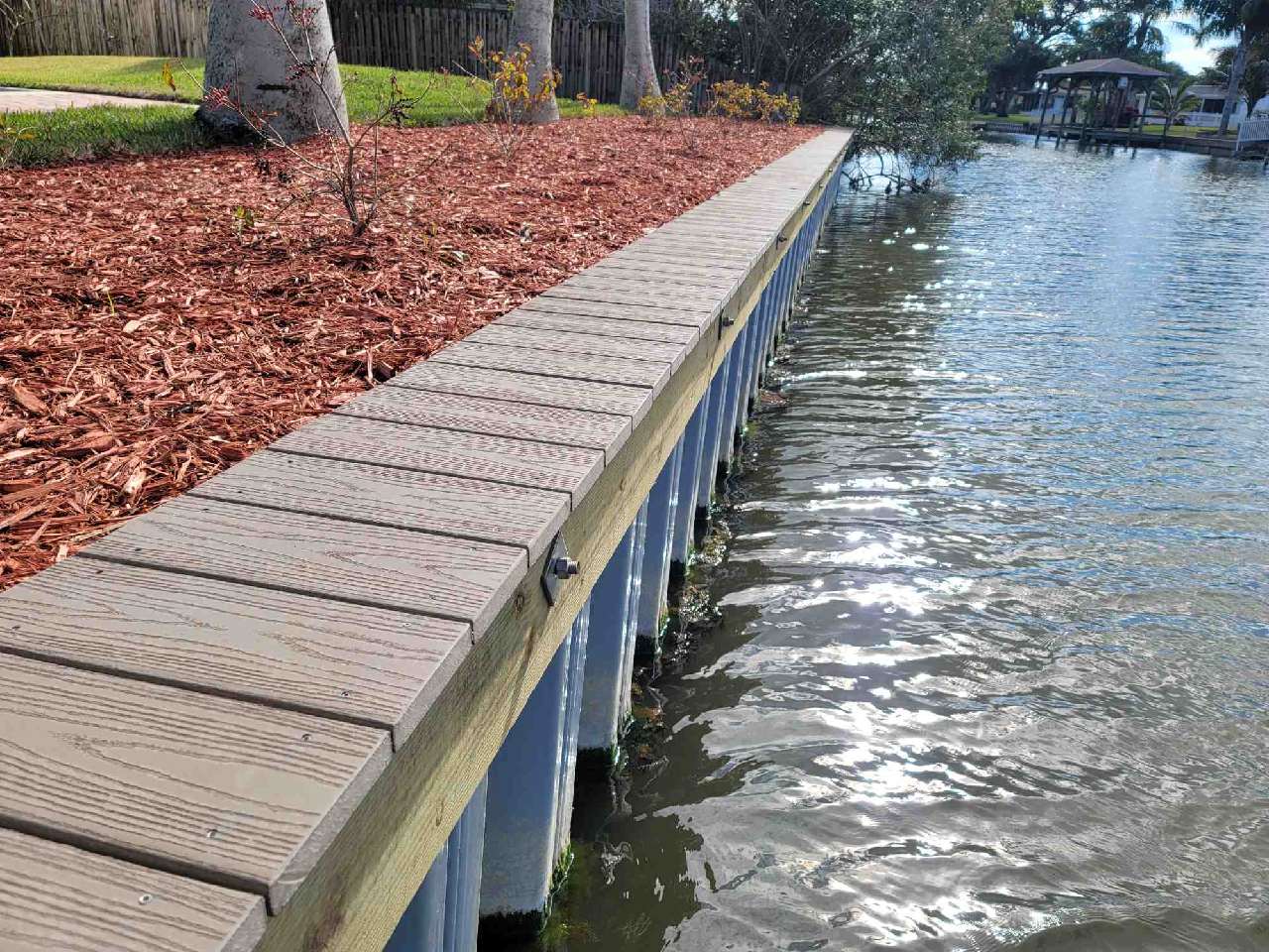 Vinyl seawall with composite cap and fresh landscaping along a residential canal
