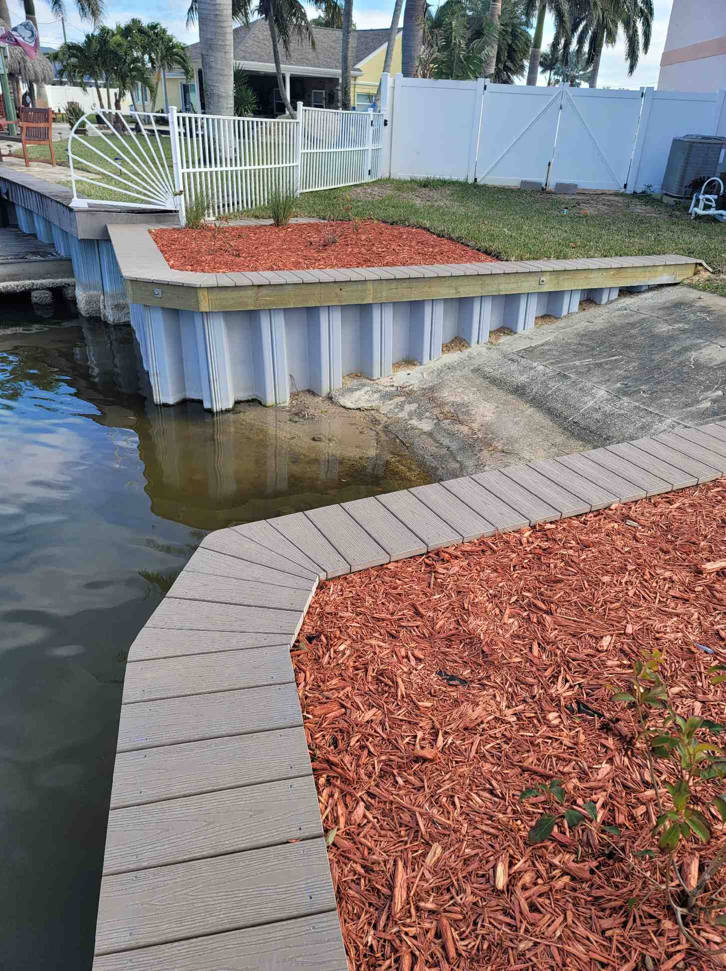 Vinyl seawall with composite cap and paver walkway behind a residential home